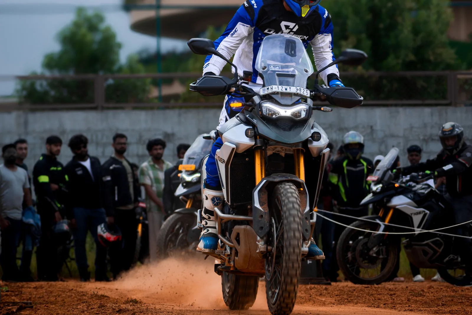 A rider on an adventure motorcycle riding through a dirt course at a local motorcycle event while spectators watch from the sidelines